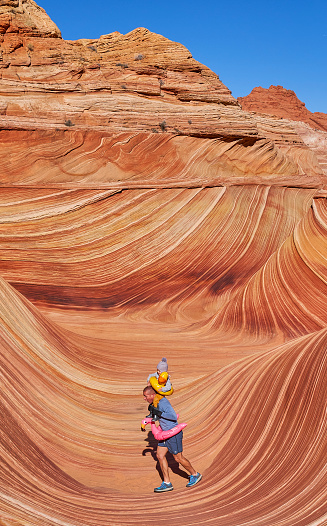 Father and toddler daughter exploring the famous Wave of Coyote Buttes North in the Paria Canyon-Vermilion Cliffs Wilderness of the Colorado Plateau in southern Utah and northern Arizona USA.
