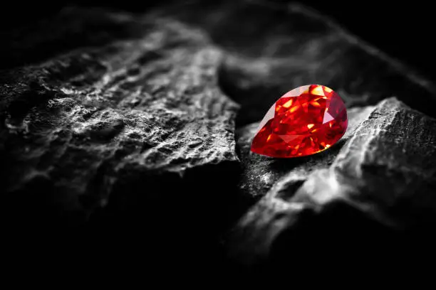 Photo of Red Ruby gemstone Round Cut on stone background, close up shot