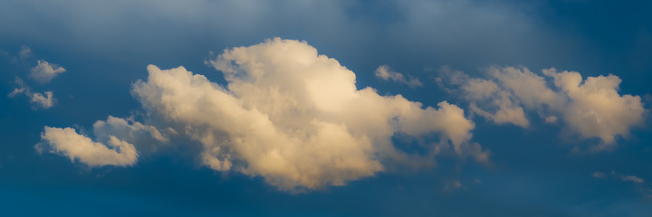 Panoramic view on Sky with dramatic fluffy clouds. White clouds on the sky suitable for background. Cloudy sky. Overcast. Long panoramic Banner