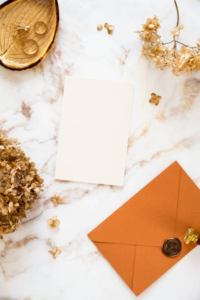istock Luxury wedding stationery set top view. Wedding invitation card template, bronze envelope, dry flowers on marble desk table. 1387352203