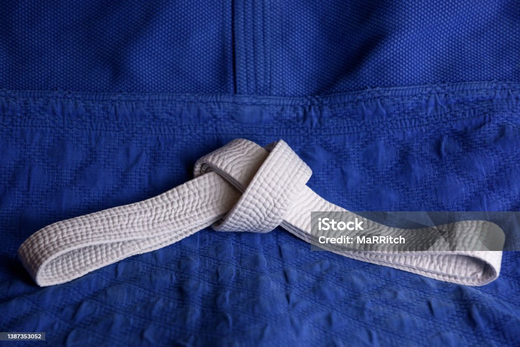 White judo, aikido or karate belt on blue budo gi. Concept is applicable to sports, business or education Aikido Stock Photo