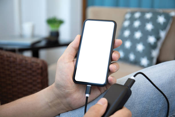 istock Man hold phone with isolated screen and power bank charge 1387357562