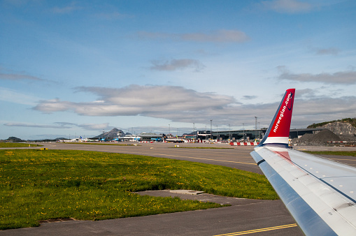 The wing of a white plane standing on an airport area. A large Norwegian Airlines airliner at the airport in Bergen.