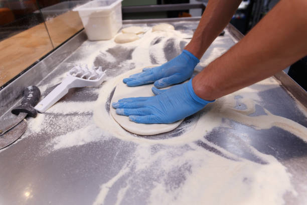 istock Making dough by male hands in blue rubber gloves on table background. 1387358398
