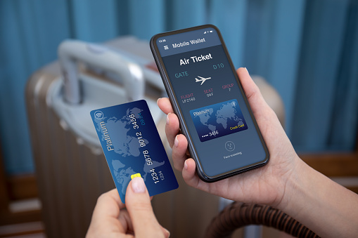 female hands hold phone with airplane ticket application airlines on screen and credit card on background of luggage at airport