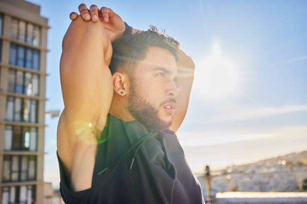 istock Shot of a sporty young man stretching while on a rooftop 1387358732