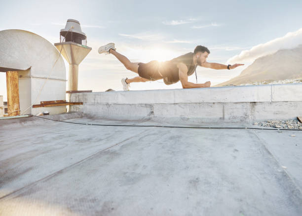 istock Shot of a man doing a single-arm plank while on a rooftop 1387358764