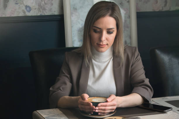 istock Young beautiful girl drinks latte coffee in a cafe at a table 1387359674