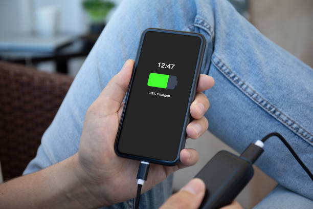 man hands holding phone charged battery connected to powerbank charge - full screen imagens e fotografias de stock