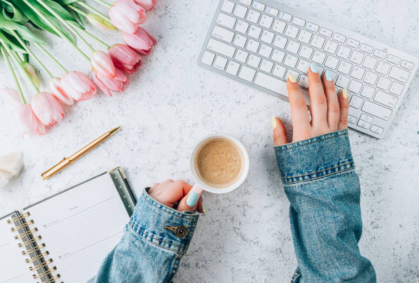 istock Feminine workspace for online work with keyboard, tulip flowers, office supply and coffee on a white background. Distance study concept 1387368193