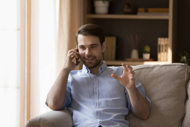 istock Relaxed happy young Caucasian man holding cellphone call conversation. 1387372782