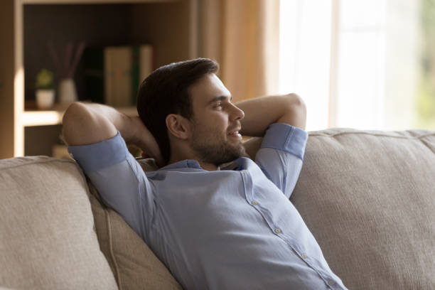 istock Smiling carefree millennial man resting on comfortable couch. 1387372786