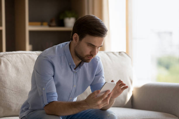 istock Concentrated young man using smartphone at home. 1387372790