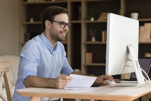 istock Happy young businessman in eyeglasses working at home office. 1387372809