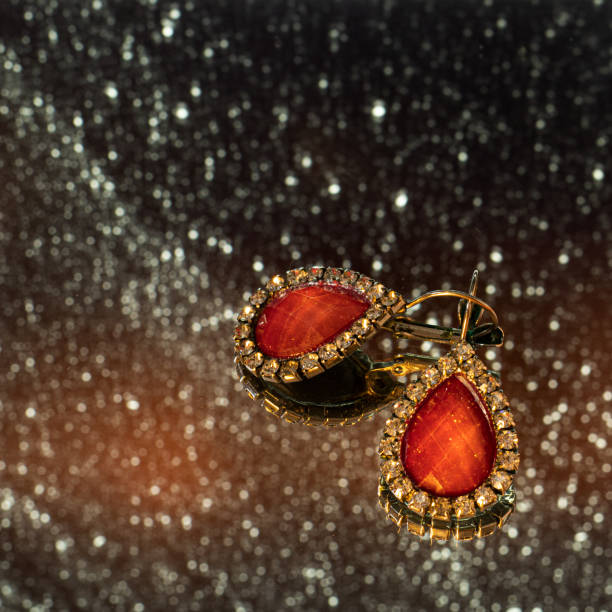 Two golden earrings with a red jewel in its center