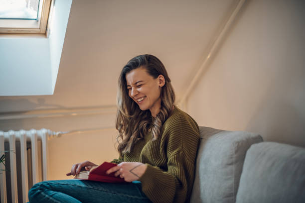 istock Woman reading a book while sitting on the couch at home 1387373423