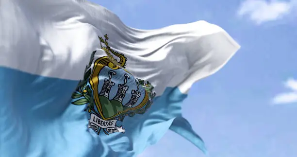 Detail of the national flag of San Marino waving in the wind on a clear day. San Marino is a small country in Southern Europe enclaved by Italy. Selective focus.