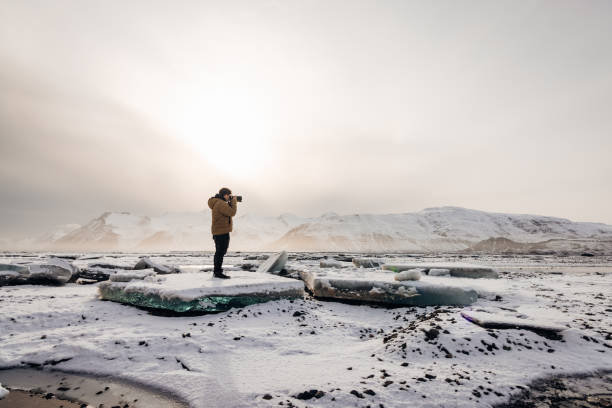 Iceland Photographer Taking Pictures on Frozen Fjord Icebergs in Sunset Twilight stock photo