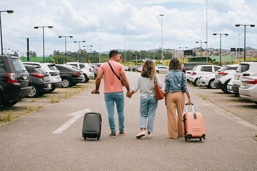 Latin family walking with suitcase at airport parking