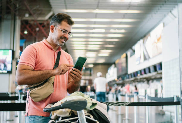 homem maduro no aeroporto esperando por check-in - pessoa do check in - fotografias e filmes do acervo