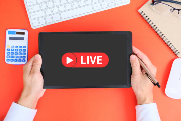 istock Hand uses a tablet to watch live streaming and use a video player app on the tablet's screen. On a red background 1387381937