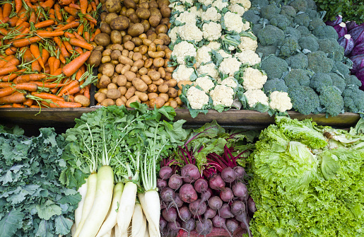 various organic vegetables in the market, pile of carrot, potatoes, broccoli, cauliflower, radish, beetroots and lettuce leaves, taken in shallow depth of field