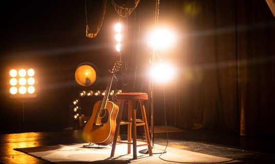 An acoustic guitar on an empty stage