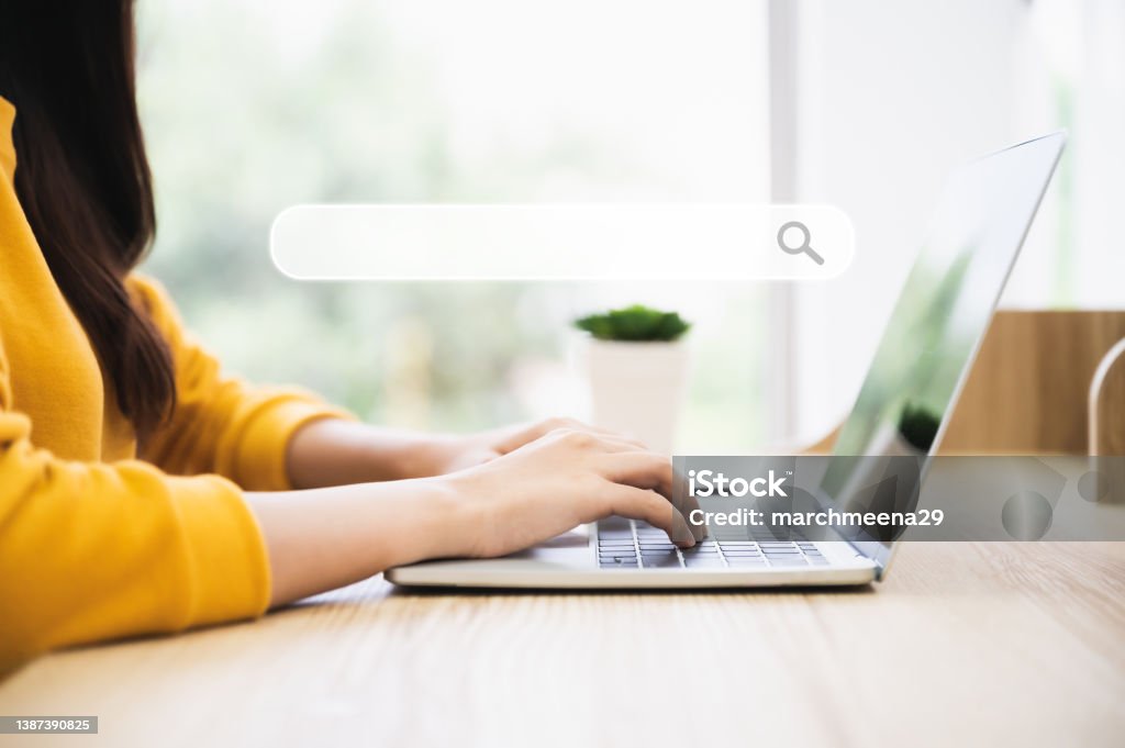 Woman using computer laptop on wood desk. She working at home Search Engine Stock Photo