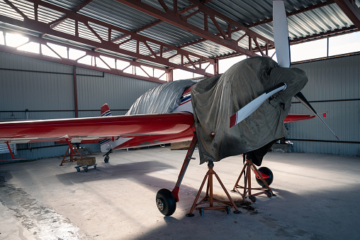 Small private lightweight propeller airplanes in hangar.