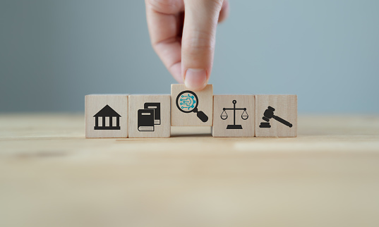 Futuristic technology for justice, law judgement concept. Artificial intelligence (AI) ,machine learning for law business. AI lawyer. Hand holds wooden cubes with AI symbols on smart grey background.