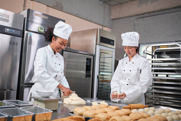 istock Female chefs in uniforms prepare to bake bread and pastry in stainless kitchen. 1387397036