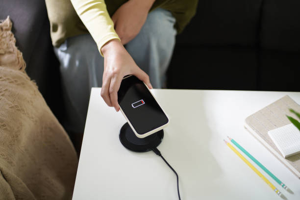 istock Charging mobile phone battery with wireless charging device in the table. Smartphone charging on a charging pad. Mobile phone near wireless charger Modern lifestyle technology concept. 1387401507