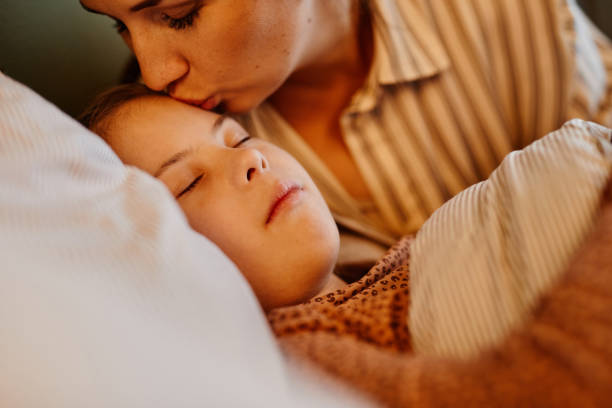 istock Mother Kissing Daughter at Bedtime 1387407123