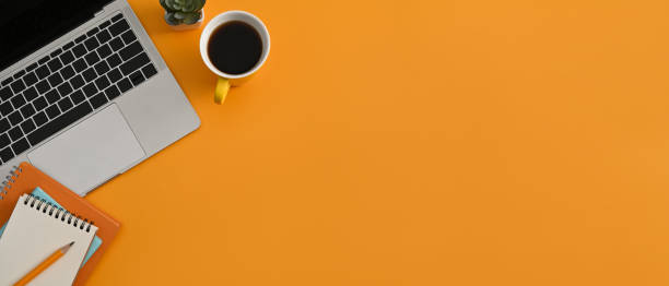 istock Computer laptop, coffee cup and notebook on yellow background with copy space. Horizontal photo, Top view. 1387412426