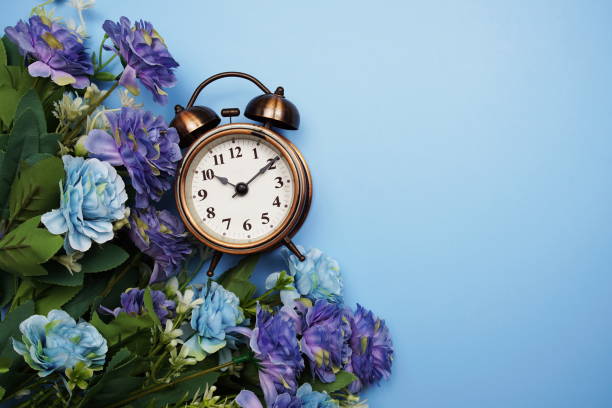 istock Alarm clock with flower frame decoration on blue background 1387414804