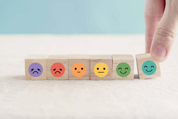 Hand choosing happy smile face wooden block, good feedback rating and positive customer review, mental health assessment, child wellness,world mental health day,think positive, emotional scale concept stock photo