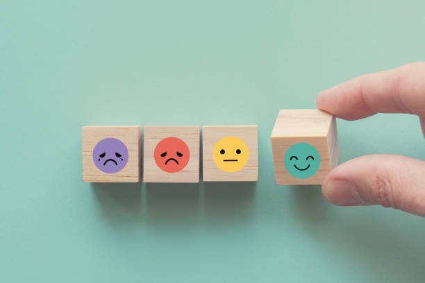 Hand choosing happy smile face wooden block, good feedback rating and positive customer review, mental health assessment, child wellness,world mental health day, think positive, compliment day concept mano eligiendo sonrisa feliz cara bloque de madera, buena calificación de retroalimentación y revisión positiva del cliente, evaluación de salud mental, bienestar infantil, día mundial de la salud mental, pensar positivo, concepto de día de cumplido