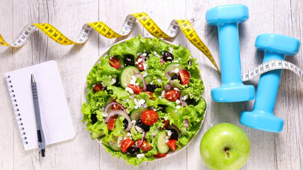 istock diet food concept- salad with dumbbell and meter 1387415992