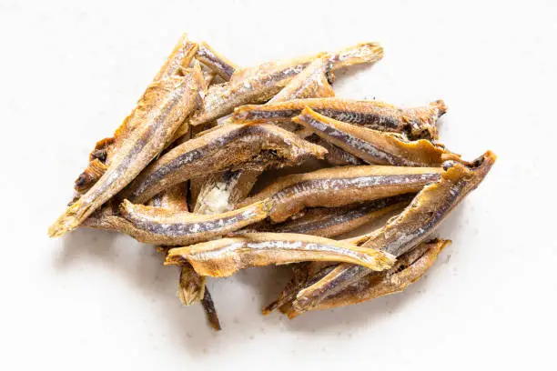 Photo of handful of dried anchovy fishes close up on gray