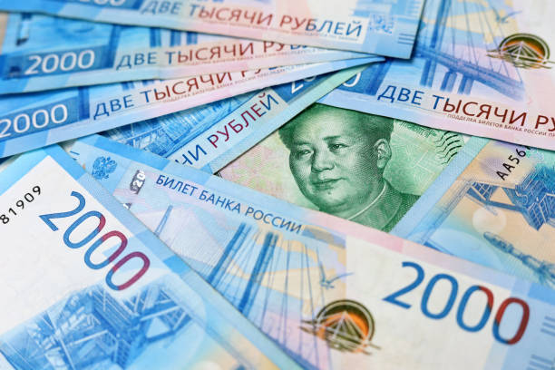 Chinese yuan banknote surrounded by russian rubles stock photo