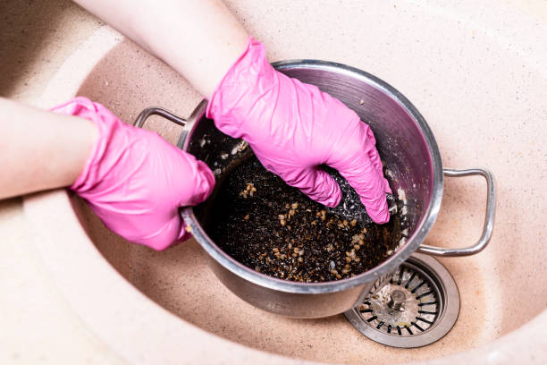 hands clean saucepan with burnt food with sponge