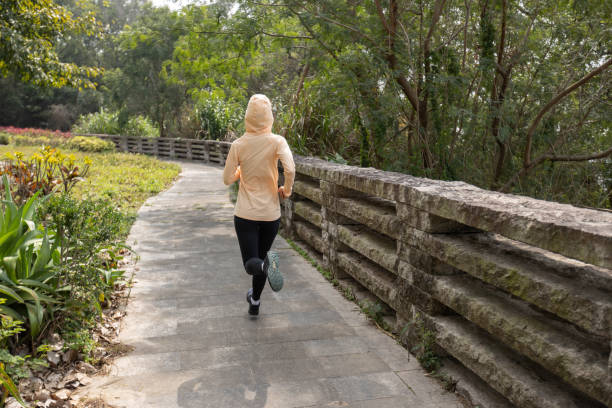 istock Asian woman jogging in park 1387421975