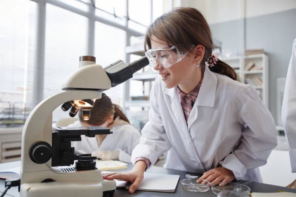 istock Excited Girl Looking in Microscope in Science Lab 1387422069
