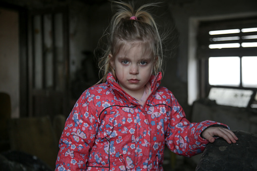 Portrait of little sad girl in ruined building. Refugees, war crisis, humanitarian disaster concept.