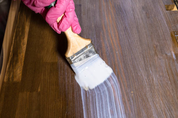 istock gloved hand varnishes a stained wooden board 1387423533