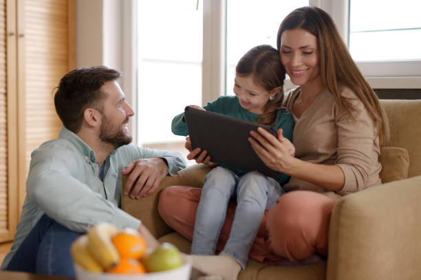 istock Happy parents and their daughter using digital tablet at home 1387424290