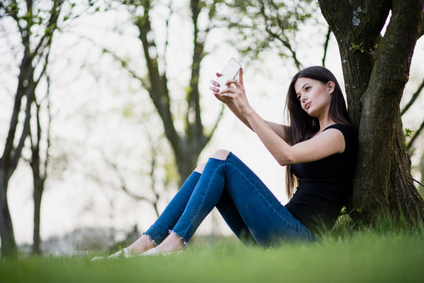 istock Young woman taking selfie in the park 1387425037