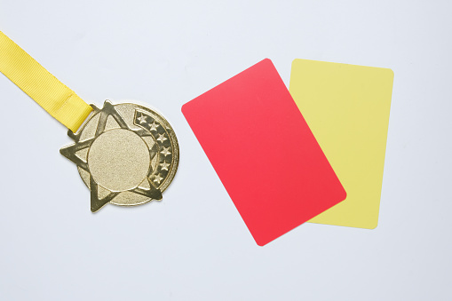 A picture of gold medal with red and yellow card. Sports disqualification concept.