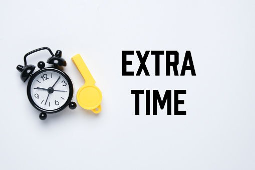 A picture of alarm clock and whistle with the word extra time. Extra time concept.
