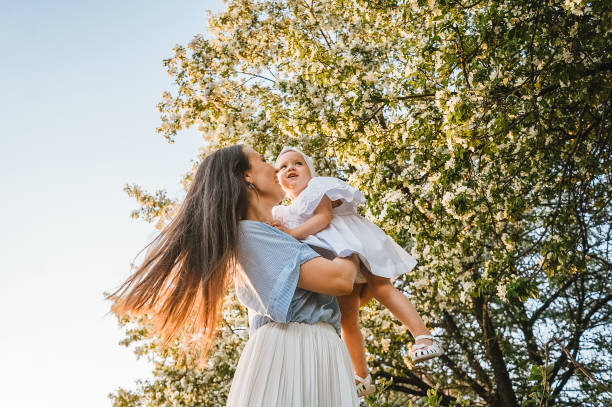 mutter und kleine tochter in der nähe von blühendem apfelbaum. - family summer portrait nature stock-fotos und bilder